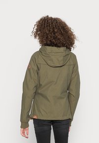 Zelená bunda s kapucí vyrobená z lehkého materiálu, s kapucí na stahování a hnědým logem na levém rukávu. Jednoduchý design, žádné vzory.