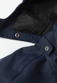 Tummansininen takki, jossa on sileä ja kestävä kangas, musta sisus, metalliset nappikiinnitykset sekä muotoiltu kaulus ja hihansuut.