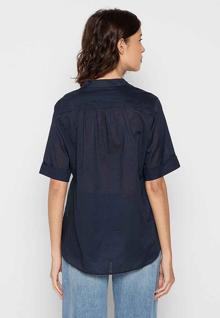 Navyblaues kurzärmliges Hemd aus leichtem Stoff, mit Kragen, gerafftem Rücken und aufgerollten Ärmeln. Moderater Schnitt mit glatter Textur.