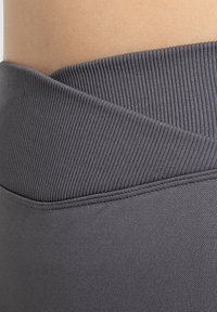 Graues Stretchmaterial mit einem gerippten Bunddesign und glatter Textur, das einen umgeschlagenen Saum und flache Nähte aufweist.