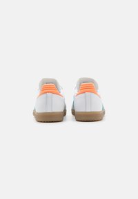 Zapatillas blancas con parte trasera texturizada y acentos laterales en color turquesa. Presenta tiradores en el talón de color naranja y suela de goma. Material de cuero suave.