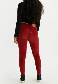 Jeans rojos ceñidos con una textura suave, que presentan una cinturilla y dos bolsillos traseros. Parche del logo en la cintura trasera sobre el bolsillo derecho.