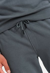 Graue Sweatpants aus einem weichen Baumwollmix, mit einem gerippten Bund, verstellbarem Kordelzug mit schwarzen Enden und Seitentaschen.