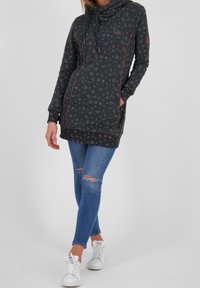 Czarna bluza z kapturem w ciemnoszarym kolorze z wzorem małych, jasnych kółek. Posiada boczne kieszenie oraz pomarańczowe akcenty szwów. W połączeniu z niebieskimi dżinsami.