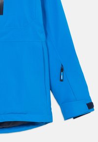 Blå vattentät jacka med halvdragkedja, justerbara ärmslut och en ficka med dragkedja på ärmen. Slät tygtextur.