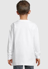 Long-sleeve white cotton T-shirt with a round neckline, straight cut, and rolled cuffs, shown from the back.
