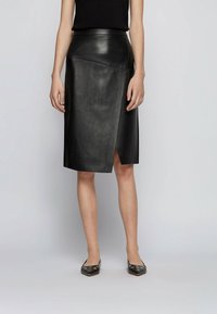 Musta nahkahame, jossa on vinosauma-designi, sivuhalkio ja sileä pinta. Yhdistetty mustien litteiden kenkien kanssa.