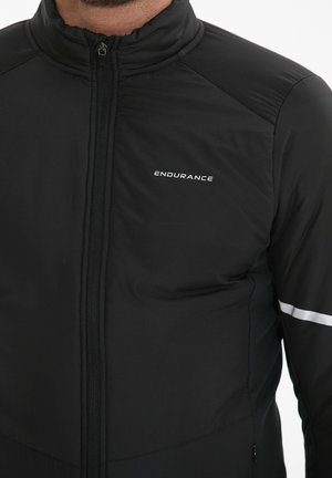 Schwarze Sportjacke mit hohem Kragen, Reißverschluss und reflektierenden Akzenten. Hergestellt aus leichter, glatter Material mit enganliegendem Schnitt.