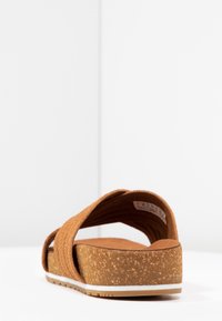 Sandali in sughero marroni con tomaia in tessuto testurizzato, ampia design incrociato e suola bianca. Leggeri e dotati di soletta imbottita.