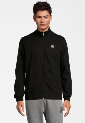 Giacca nera con zip realizzata in tessuto liscio, con colletto alto e polsini elastici. Presenta un piccolo logo bianco sul petto sinistro.