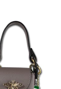 Grijze leren handtas met een gestructureerde afwerking, voorzien van een gouden bijaccent aan de voorkant en een zwarte strap met gouden hardware.