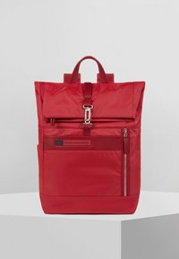 Zaino in nylon rosso di forma rettangolare, design con chiusura a rotolo, chiusura frontale a patta, accessori in argento, tasca laterale con zip e etichetta con marchio.