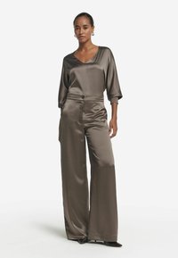 Satin tvådelat set i mörk taupe med en V-ringad topp med 3/4 längd på ärmarna och högmidjade vida byxor, med en subtil lyster.