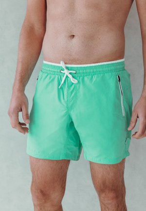 Mintgroene zwembroek van lichtgewicht stof, met een elastische tailleband en een trekkoord, en een zijzak met rits.