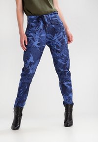 Blå kamouflage cargo-byxor med elastisk midja, två framfickor och tapered ben, tillverkade av ett lätt och strukturerat tyg.