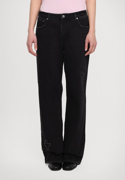 Jean large noir avec une finition délavée, présentant des coutures décoratives sur le bas des jambes et un design à cinq poches. Fabriqué en denim.