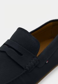 Sort læder loafersko med penny rem detalje og brunt indvendigt foer, der har en diskret tri-color stofmærke på siden.