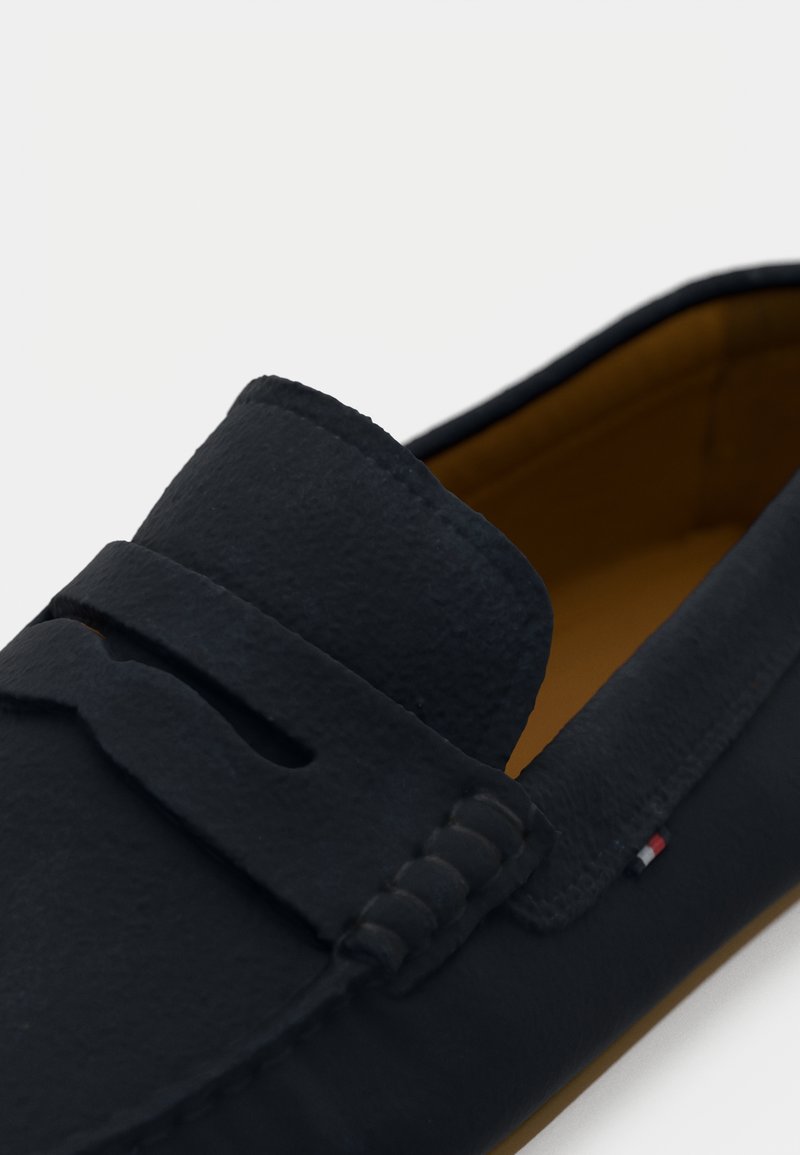 Czarne skórzane loafersy z paskiem na monety i brązowym wykończeniem wewnętrznym, z subtelną, trójkolorową metką z boku.