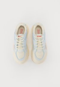 Baskets Lacoste avec une tige en maille et en cuir de couleur bleu clair et crème, présentant des lacets crème, une semelle rembourrée et des accents de logo.