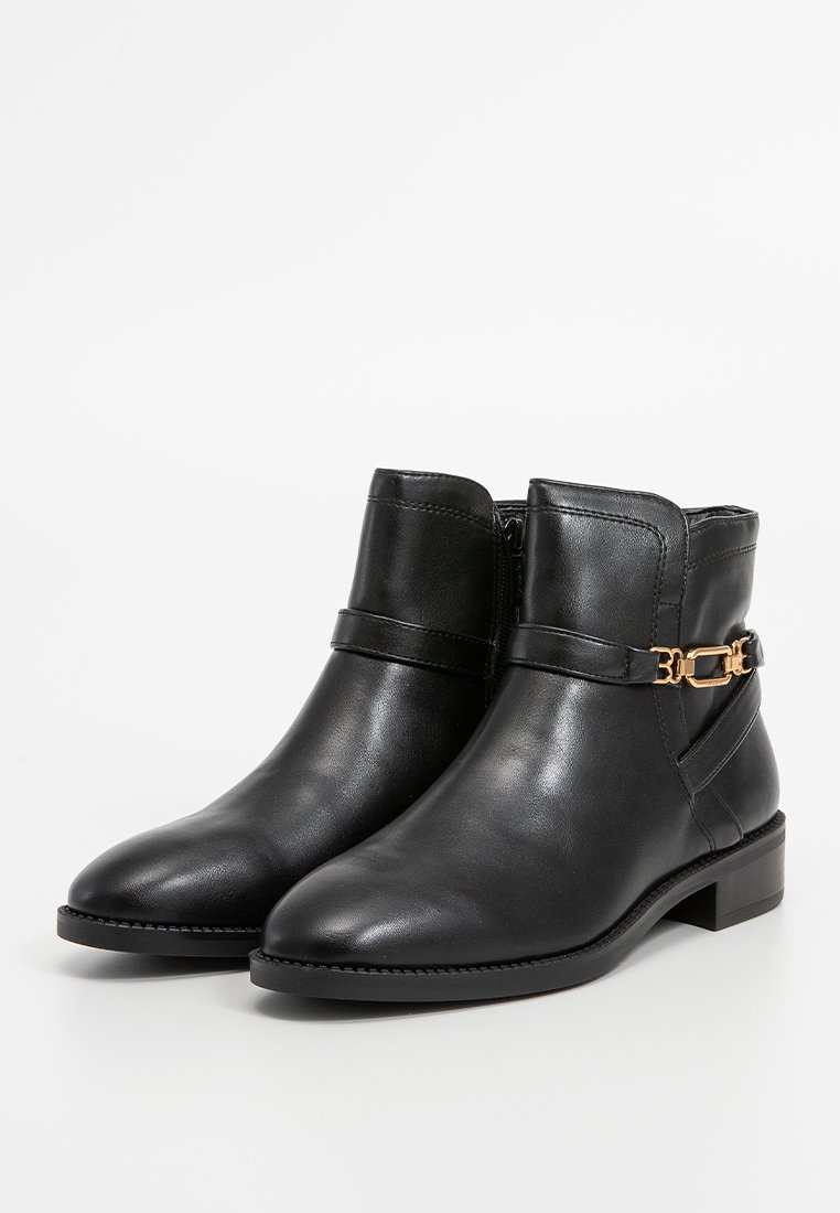 Schwarze Leder-Stiefeletten mit glatter Oberfläche, runder Fußspitze, seitlichem Reißverschluss und goldfarbenen Metallakzenten, die den Knöchelriemen betonen.