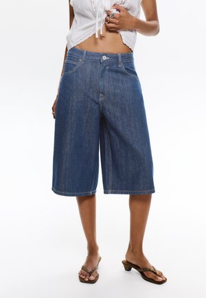 Denim culottes in dark blue, featuring a relaxed fit, mid-rise waist, and wide leg. Finished with front pockets and contrast stitching.