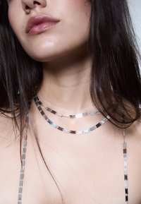 Due collane d'argento a due strati con maglie metalliche rettangolari; superfici lisce e lucide, con variazioni di colore argento e accenti neri.