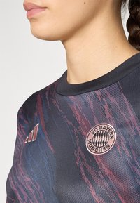 FC Bayern München shirt in donkere kleur met abstract patroon in rood en blauw. Heeft een ronde halslijn, textuurstof en logo-accent op de borst.