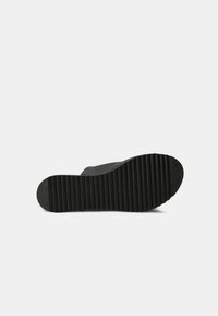 Semelle de chaussure en caoutchouc noire avec une texture nervurée, présentant un bout arrondi et des bords lisses, conçue pour l'adhérence et la durabilité.