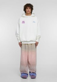 Bílá oversized mikina s nápisy "todays dreamers" a "A.b.l.a.t." v růžové a modré barvě. Gradient tepláky přecházející z pastelově růžové do fialové.