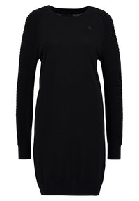 Svart tröjdress med ribbade ärmar, rund halsringning och texturerade detaljer. Slät kropp med avslappnad passform, lämplig för avslappnad användning.