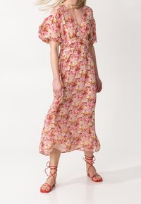 Květinové midi šaty v růžové, žluté a zelené barvě s nabíranými rukávy a výstřihem do V. V kombinaci s červenými sandály na klínu. Lehká, splývavá tkanina.