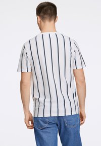 Vit kortärmad skjorta med vertikala marinblå och ljusblå ränder. Blanda bomullstyg med avslappnad passform och rundad design.