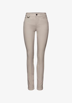 Beżowe dopasowane spodnie z kieszeniami z przodu, szlufkami na pasek, zapięciem na guzik, suwakiem oraz małym metalowym pierścieniem po prawej stronie.