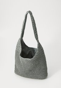 Sac à épaule tissé gris avec un extérieur texturé, une bandoulière large unique et un dessus ouvert. L'intérieur est en tissu lisse et se ferme avec un snap.