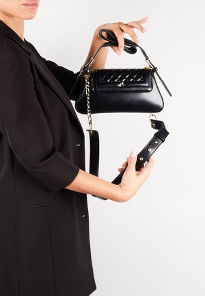 Sort håndtaske lavet af læder med en quiltet overflade, en top-håndtag og en aftagelig rem. Har guldfarvet hardware og et elegant design.