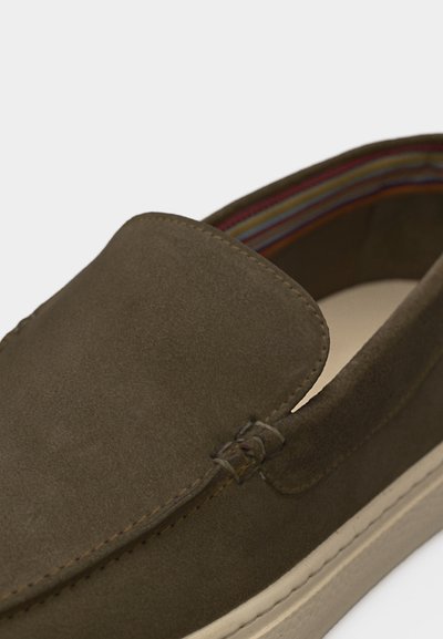 Rudas zomšinis slip-on stiliaus batelis su balta pado dalimi ir daugiarašte dryžuota vidine pamušalo dalimi, matomos siūlės ant viršutinės dalies.