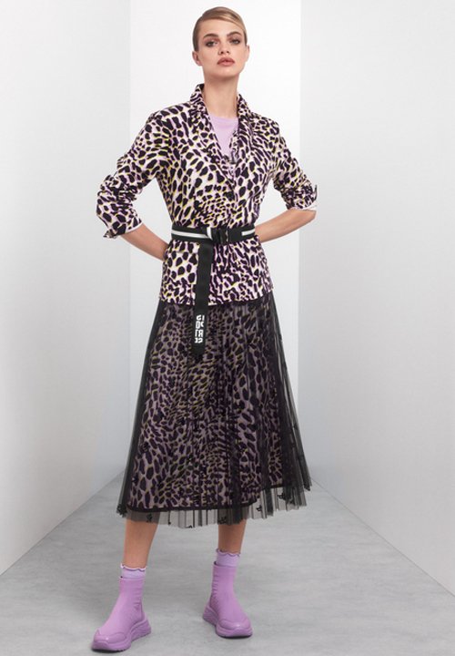 Leopardenmuster Jacke mit lila Akzenten, tailliert mit einem Gürtel und über einem schwarzen Tüllrock getragen. Das Modell trägt lavendelfarbene Knöchelstiefel.