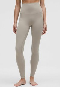 Beige Leggings mit hoher Taille aus elastischem Stoff, mit glatter Textur, figurbetontem Schnitt und dezenten Nähten.