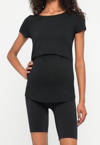 Svart graviditetstopp med korta ärmar, kort design och mjukt tyg. Matchas med svarta cykelbyxor, båda i stretchmaterial.