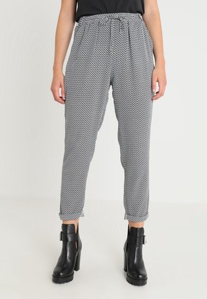 Pantalones con estampado en blanco y negro, con cintura elástica y cordón ajustable. Diseño de pierna estrecha; combinados con botines negros de tacón.