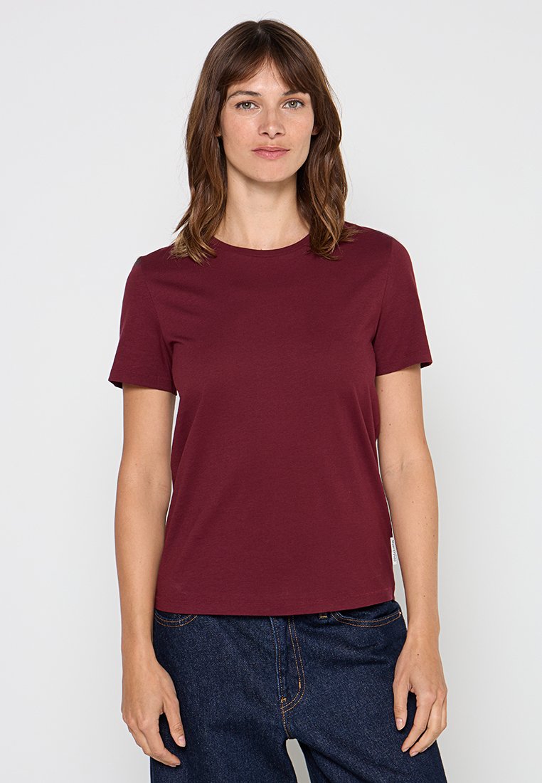 Burgunderfarbene Baumwoll-T-Shirt mit kurzen Ärmeln, Rundhalsauschnitt und geradem Schnitt. Getragen mit dunklen Denim-Jeans.