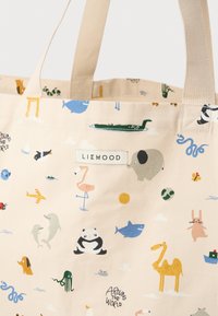 Katoenen draagtas in licht beige met kleurrijke dieren- en natuurthema prints. Heeft dubbele stoffen handvatten en een label met de tekst "LIEWOOD."