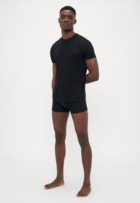 Sort t-shirt med korte ærmer og sorte boxer briefs, begge lavet af blødt stof, tætsiddende design, glat overflade og minimalistisk stil.