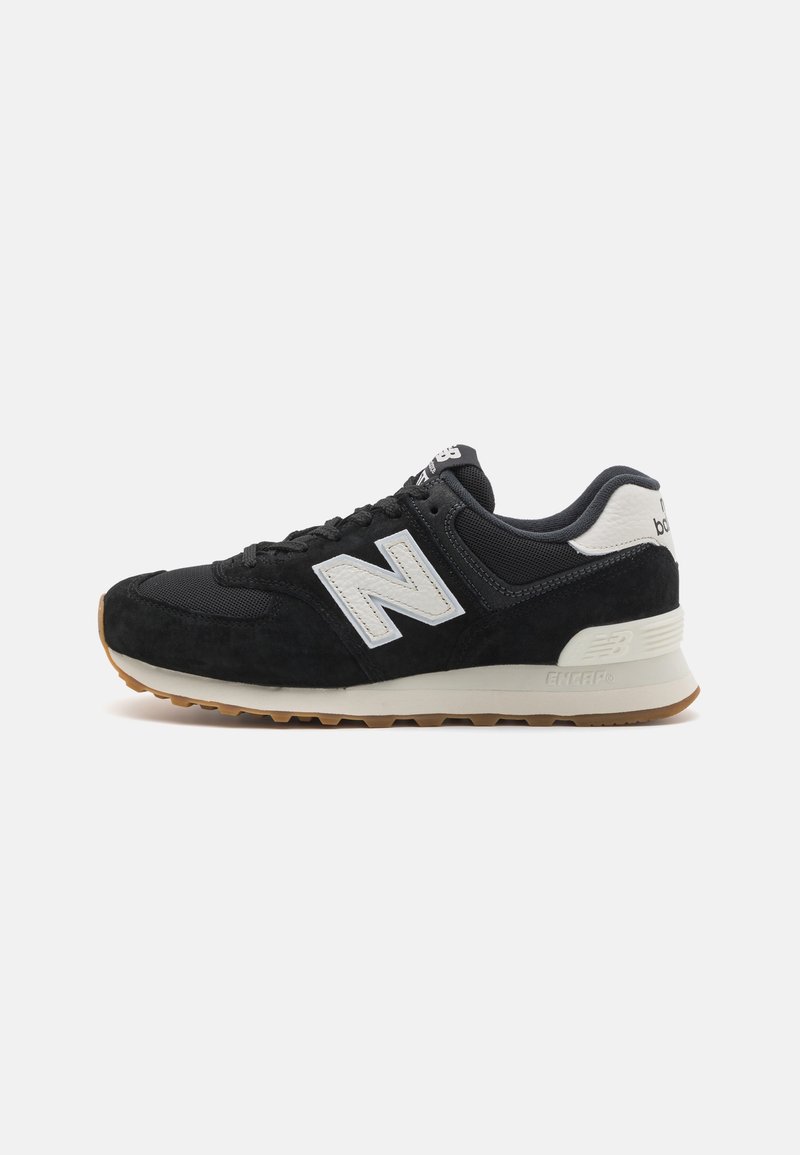 Baskets New Balance noir et blanc avec dessus en mesh et daim, logo blanc et semelle en caoutchouc naturel, montrées de profil sur fond blanc.