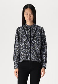 Blusa a fiori nera e blu con colletto alto, maniche lunghe a sbuffo e chiusura con bottoni frontale. Realizzata in tessuto leggero.