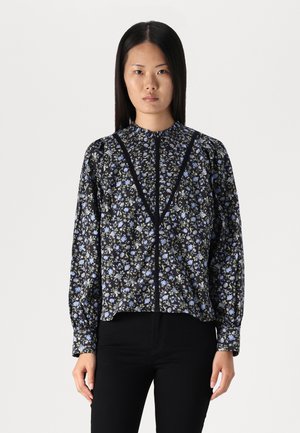 Svart og blå blomstret bluse med høy hals, lange puffede ermer og knapplukking foran. Laget av lett stoff.