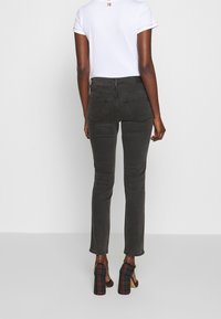 Mustat slim-fit farkut yhdistettynä valkoiseen t-paitaan, jossa on värikkäitä yksityiskohtia. Kengät ovat korolliset ja niiden kuosina on ruutukuosi.