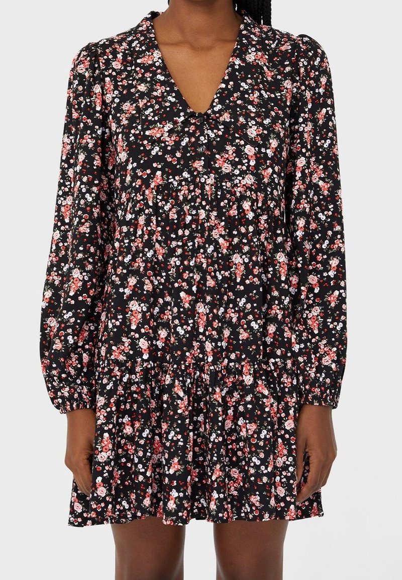 Zwart bloemenjurk met lange poefmouwen, een V-hals, geplooide details en een uitlopende rok, versierd met roze en witte bloemen.