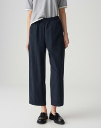 Pantalons cropped bleu marine avec une taille élastique, dotés de poches latérales et d'une finition texturée. Portés avec un haut gris à manches courtes et des chaussures noires.