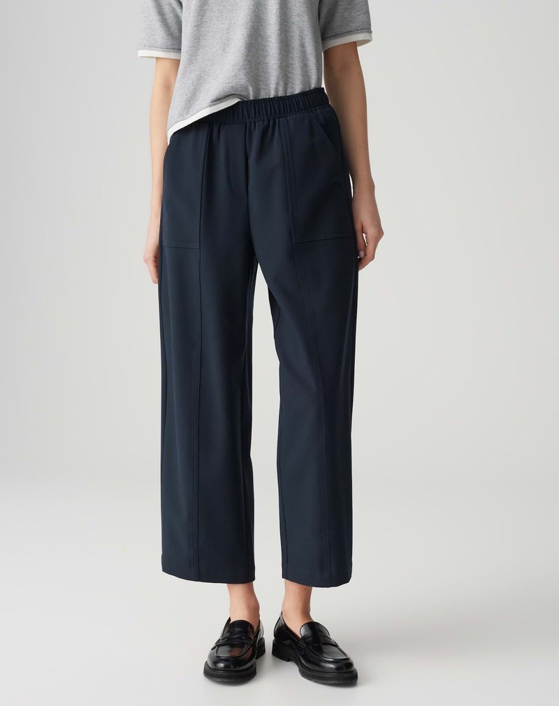 Pantalons cropped bleu marine avec une taille élastique, dotés de poches latérales et d'une finition texturée. Portés avec un haut gris à manches courtes et des chaussures noires.